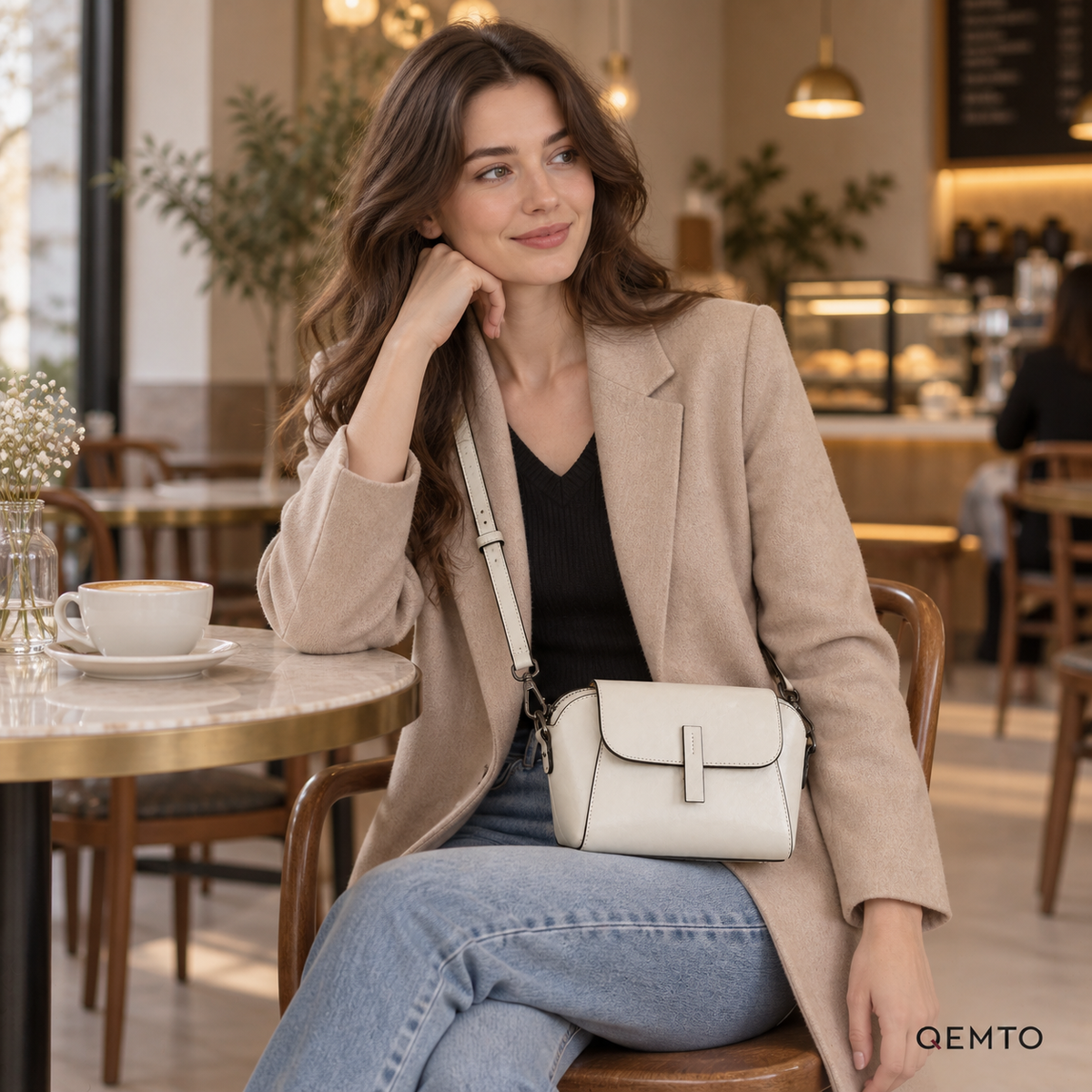 QEMTO Nora Crossbody Bag in White worn by a model at a cafe table