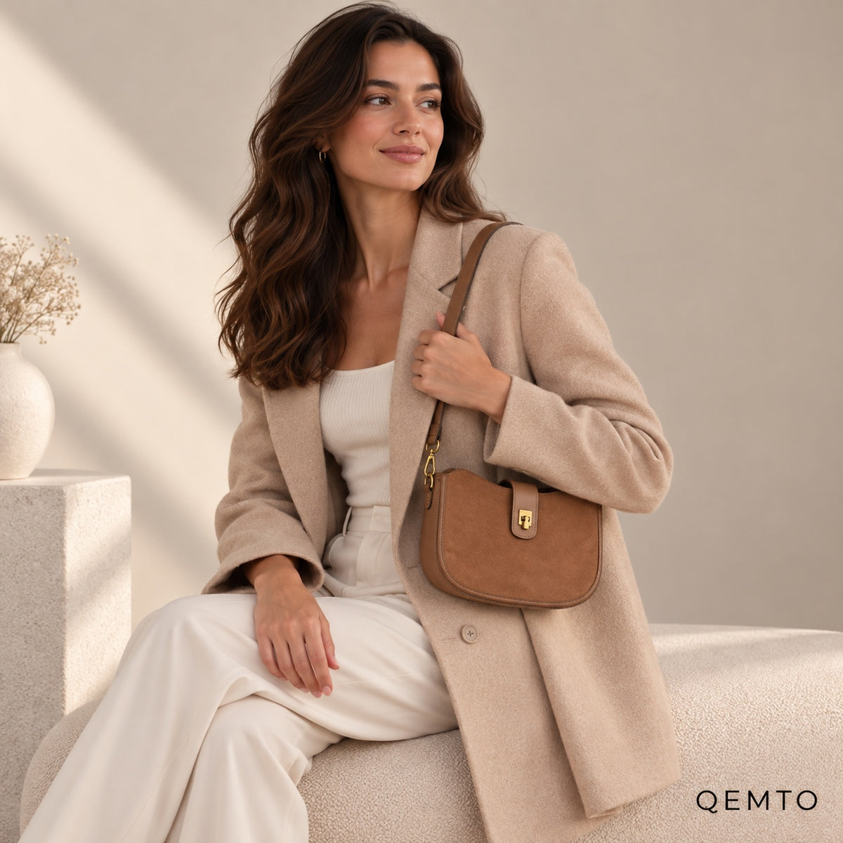 QEMTO Mara Brown Leather Saddle Bag worn on the shoulder by a seated model